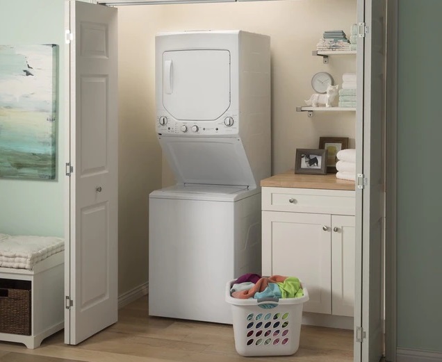GE GUD24ESSMWW stacked washer dryer unit in a laundry closet next to a basket of clothes