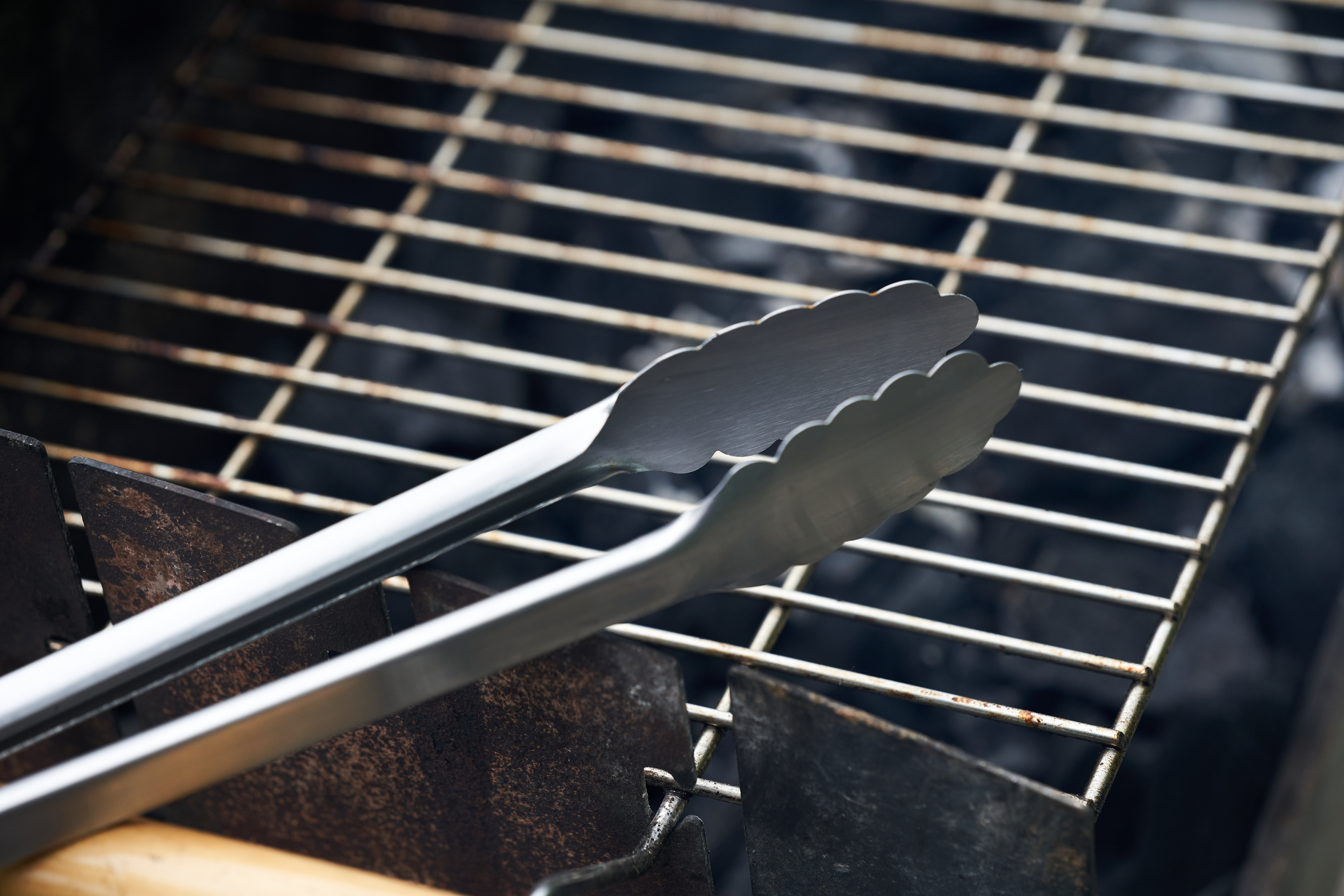 A close up of metal tongs on grill grates