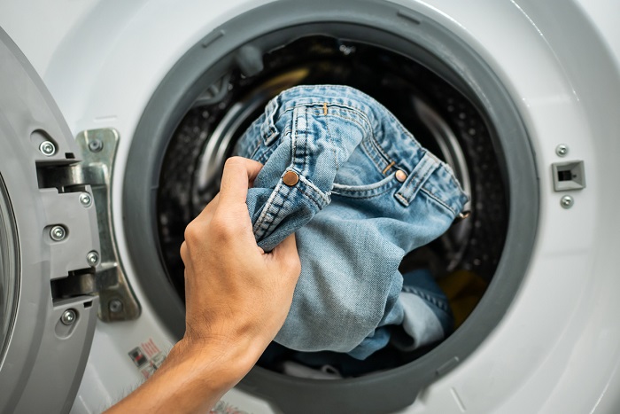 Putting Jeans into the washing machine.