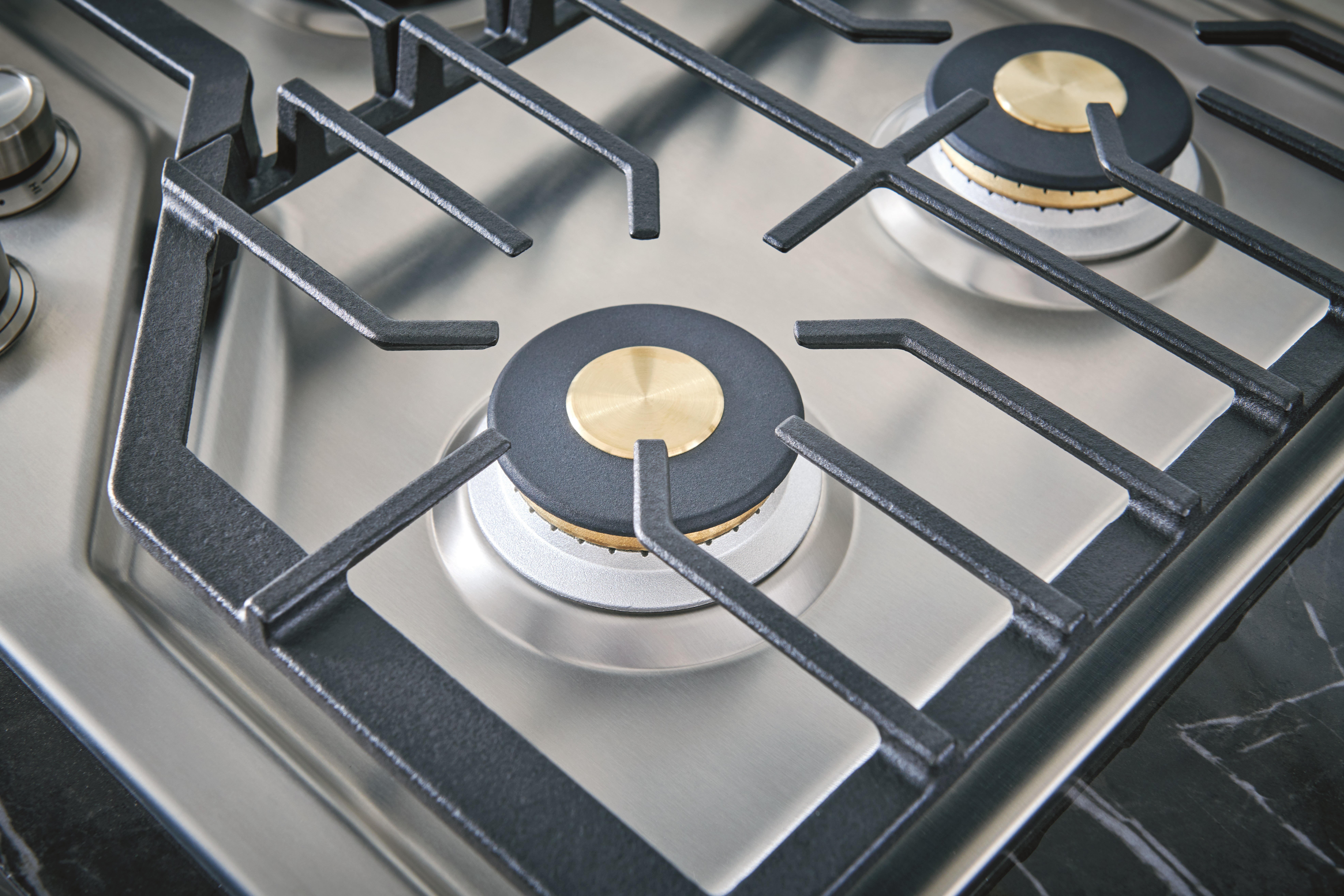 Closeup of bronze burners on Monogram U24051352 gas cooktop 