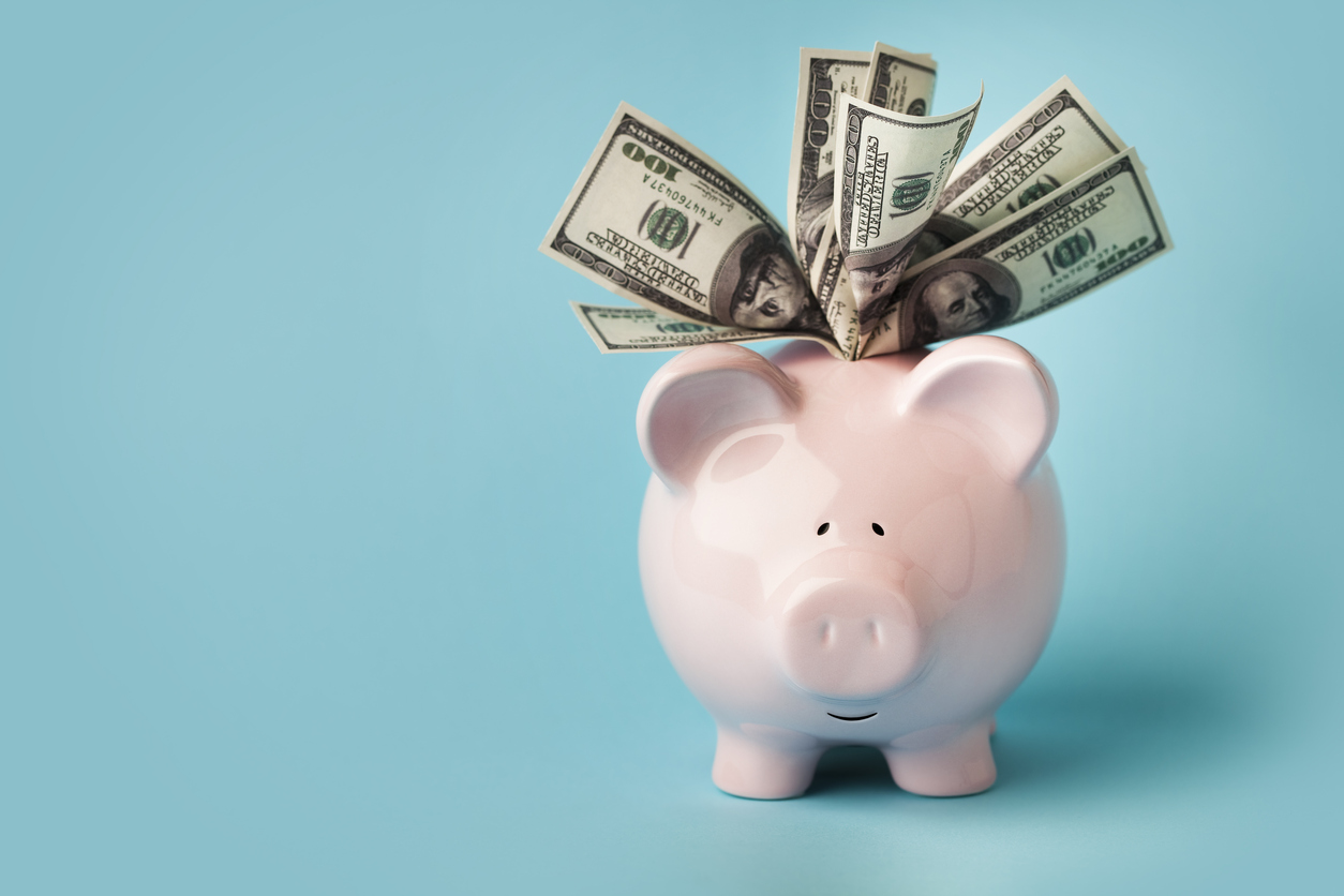 pink piggy bank with 100 dollar bills against a sky-blue background
