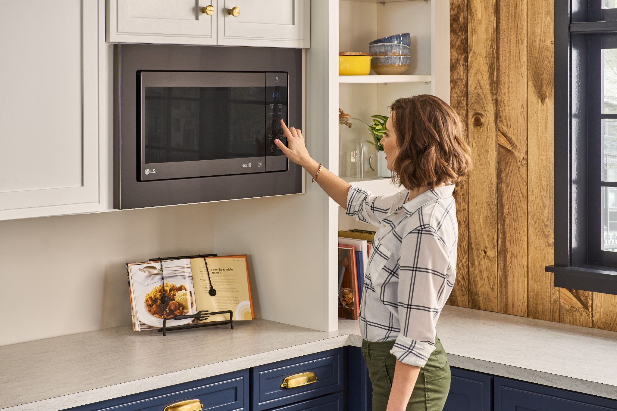Woman in striped shirt selects a cook setting on Samsung LMC2075BD over the range microwave