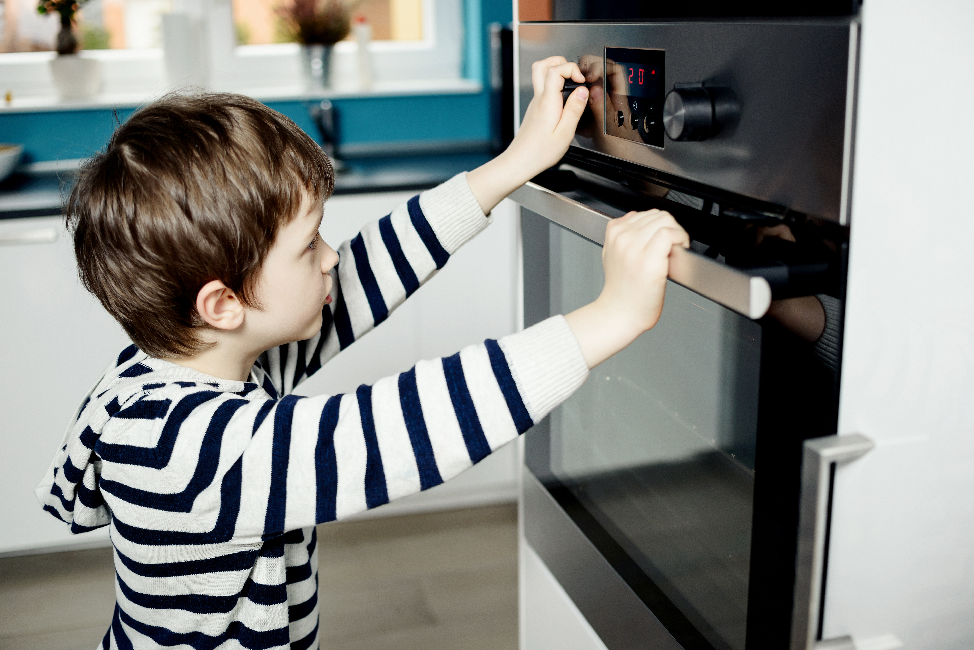 A boy in a striped sweater looking into an oven