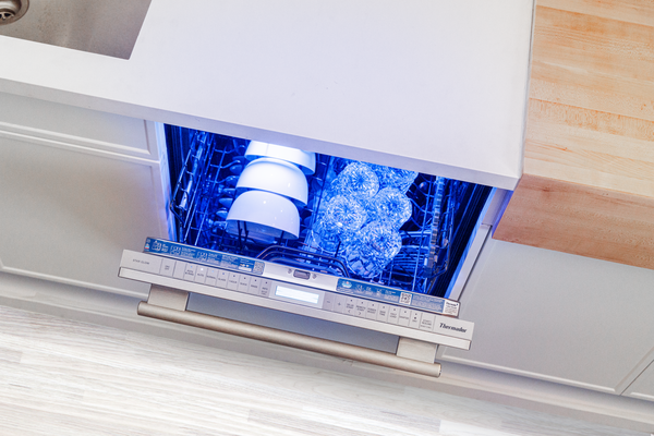 An overhead view of a Thermador dishwasher with its door open and its Star Glow interior on
