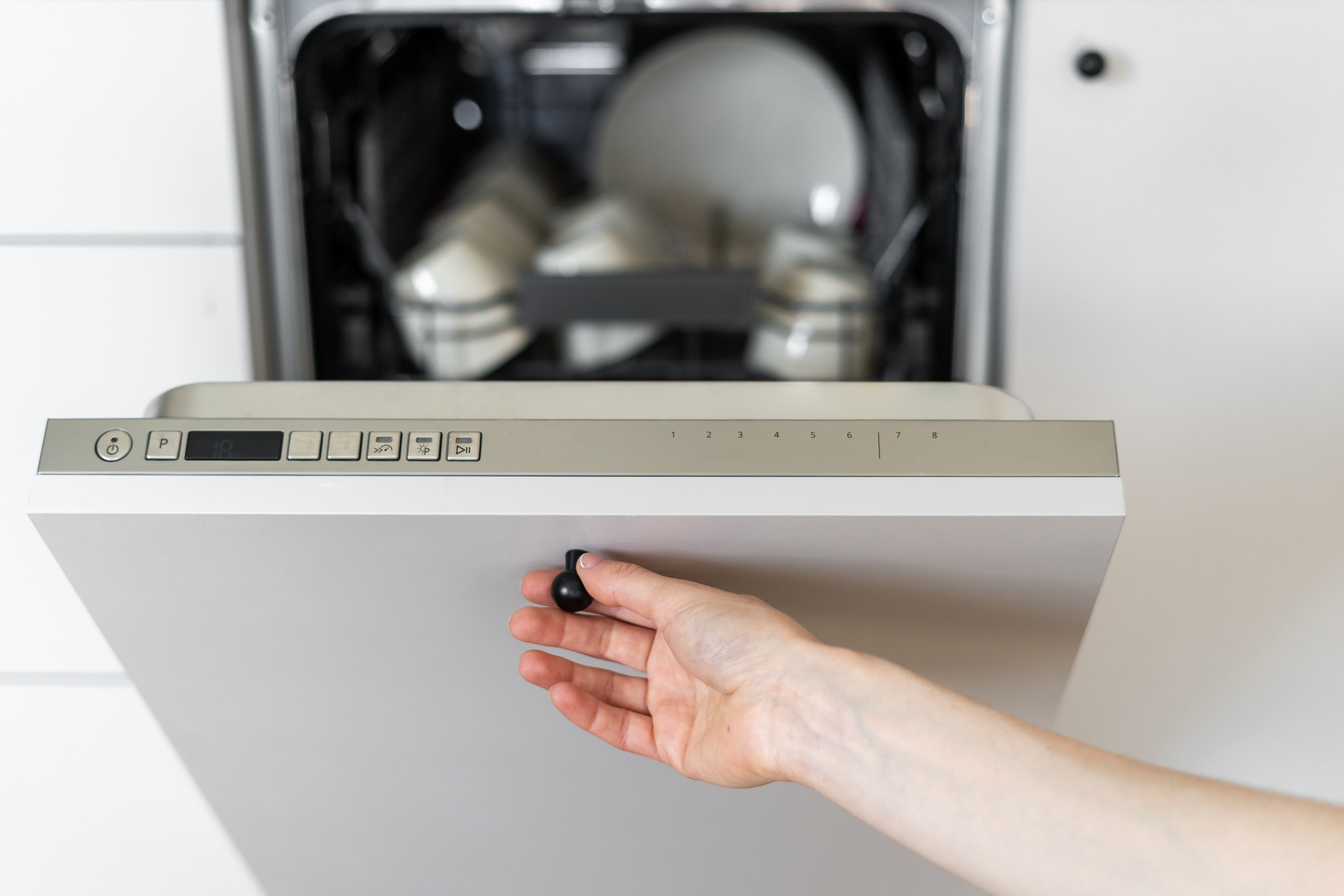 A person opening a panel-ready dishwasher 