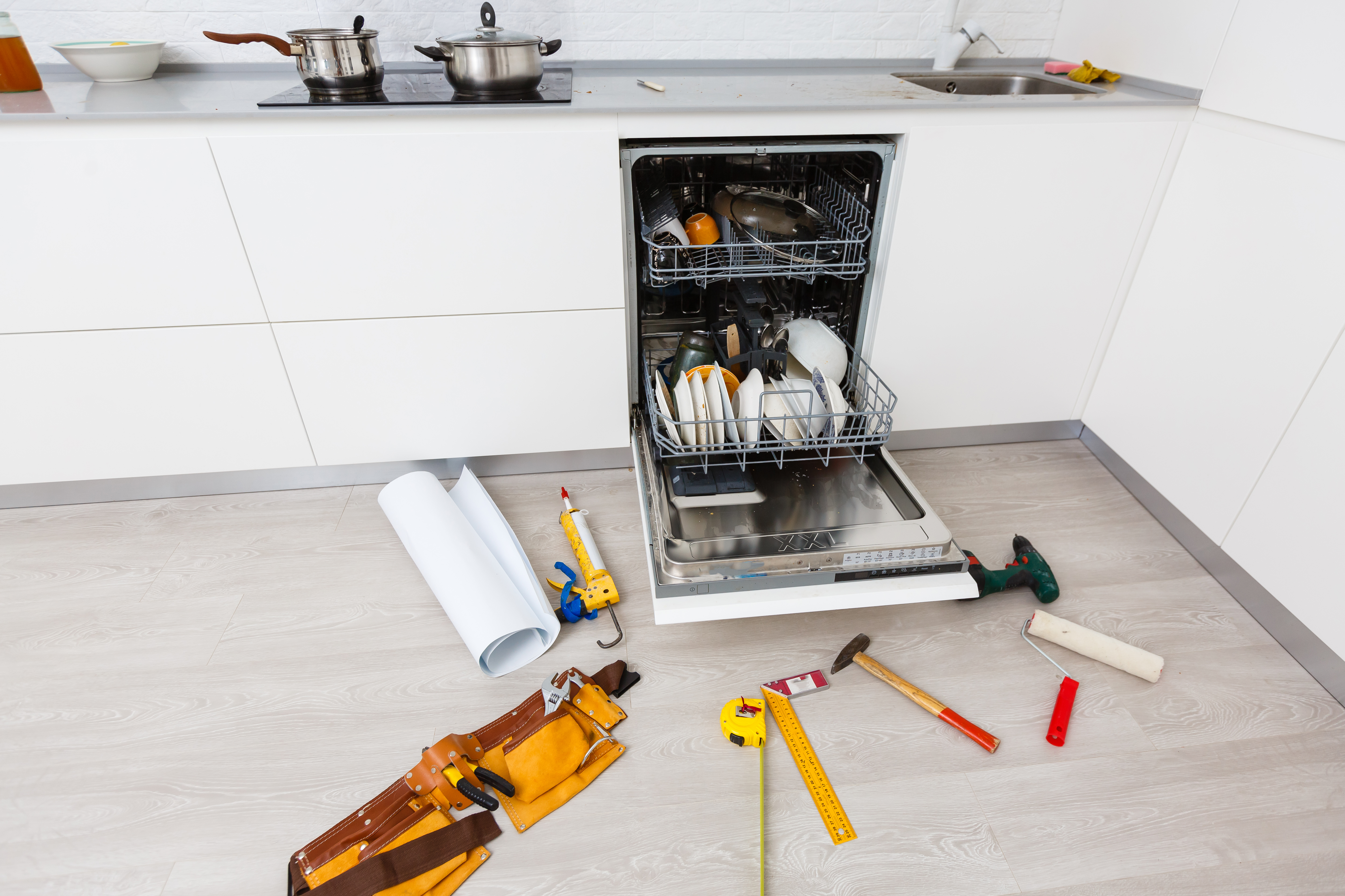 repairman tools laying down broken dishwasher 