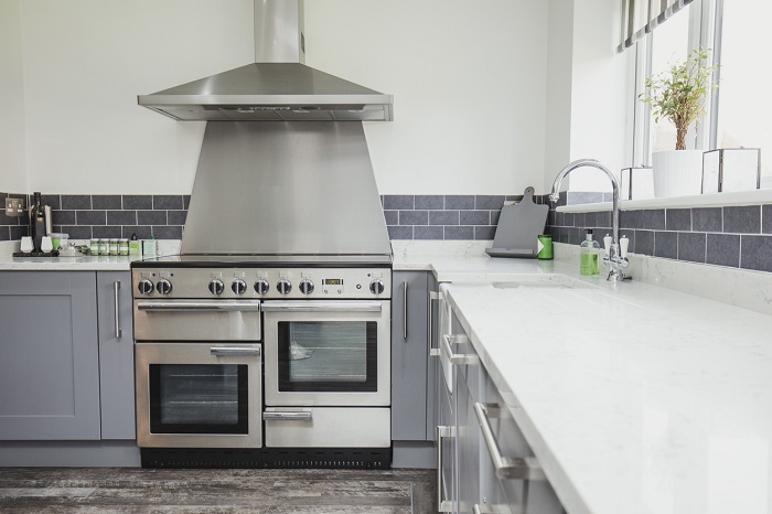 Shot of a contemporary domestic kitchen with a double oven range and overhead hood. 