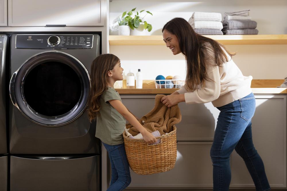 mom and daughter do laundry together with Electrolux front load washer and dryer 
