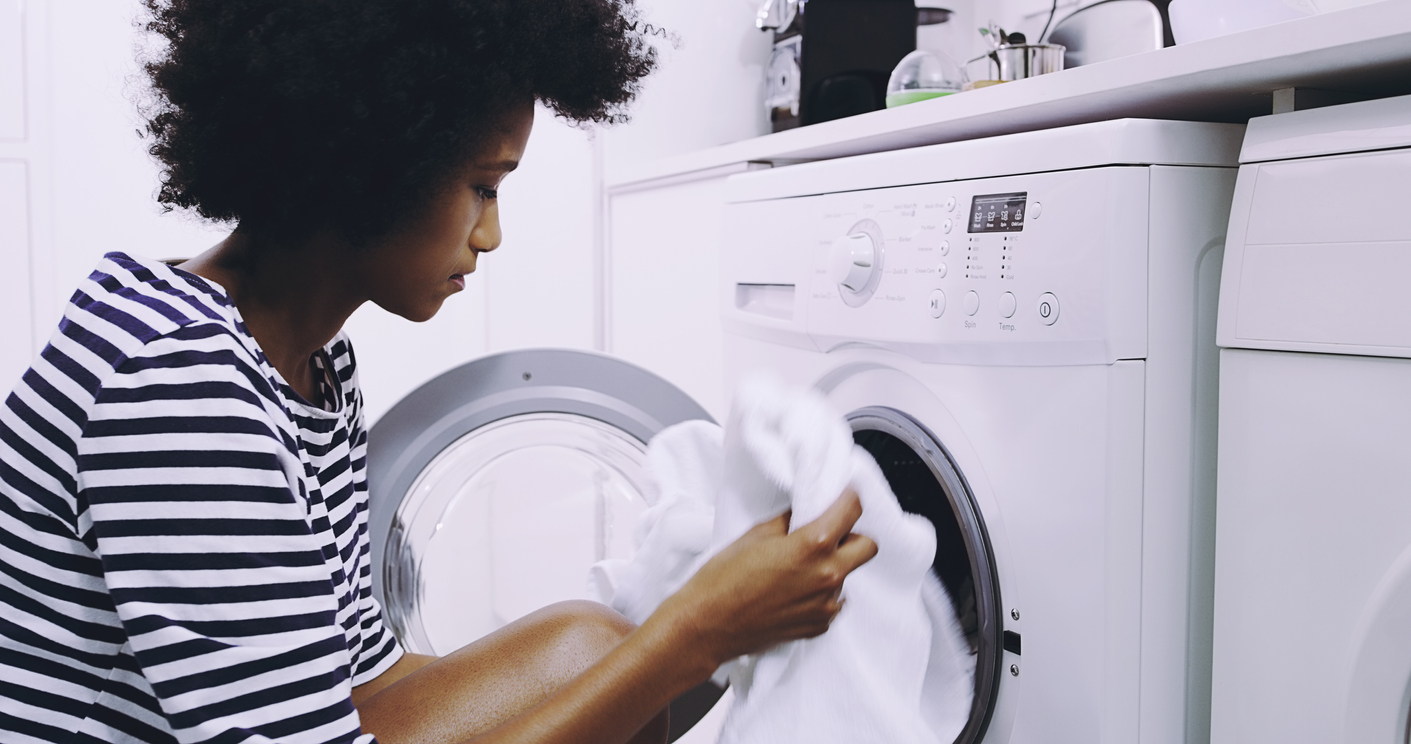 A woman pulls clean clothing from a dryer