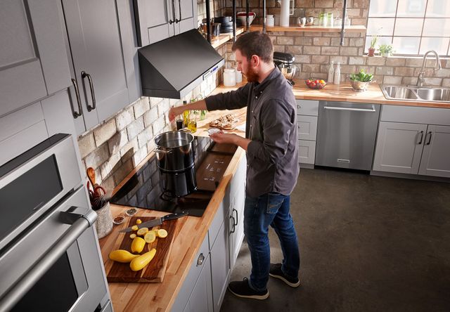 Overhead view of a man cooking in a modern kitchen on a KitchenAid range