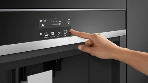 A hand goes to make coffee using a Fisher and Paykel coffee maker