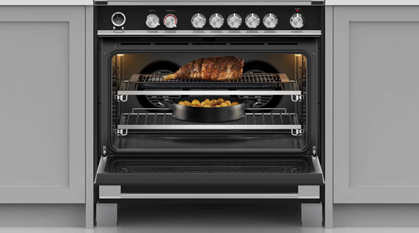 A Fisher & Paykel range in a black finish is open revealing the food it roasts inside