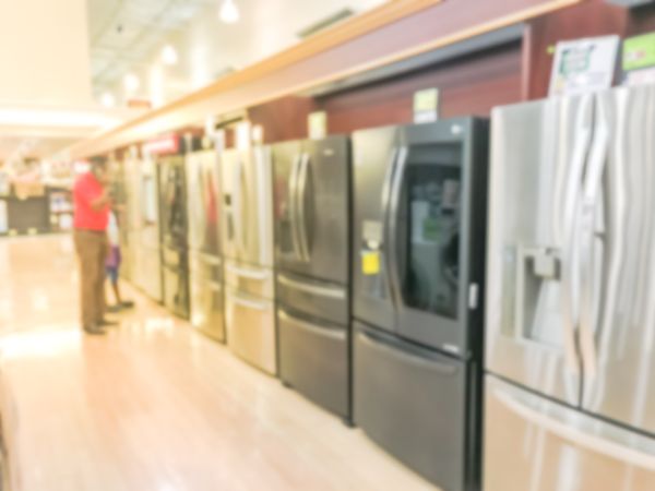 A blurry image of people shopping for refrigerators in a store 