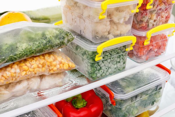 A variety of frozen vegetables in containers inside of a freezer