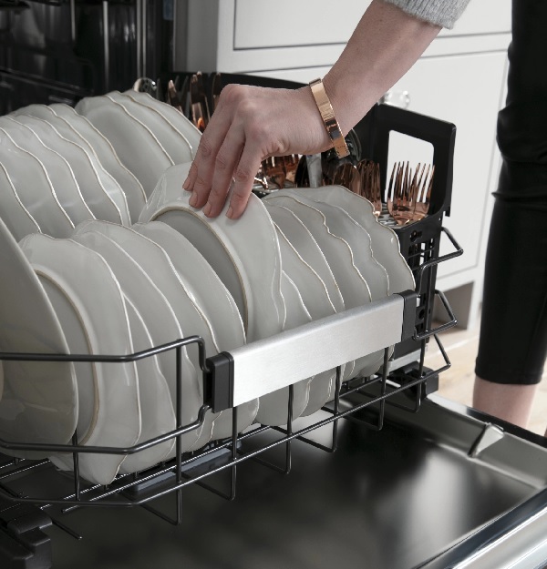 A person removing a plate from a Café dishwasher 