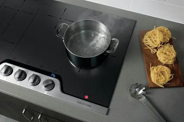 A person cooking steaks on a griddle on the Frigidaire Professional FPIC3677RF induction cooktop