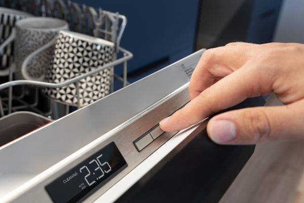 A person pressing a button on a dishwasher 