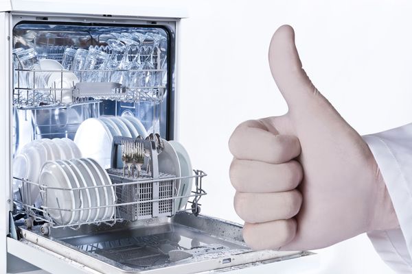 A hand giving a thumbs-up in front of a dishwasher 
