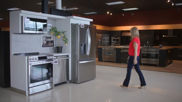 A Fred’s Appliance associate shown near a full kitchen suite inside a store 