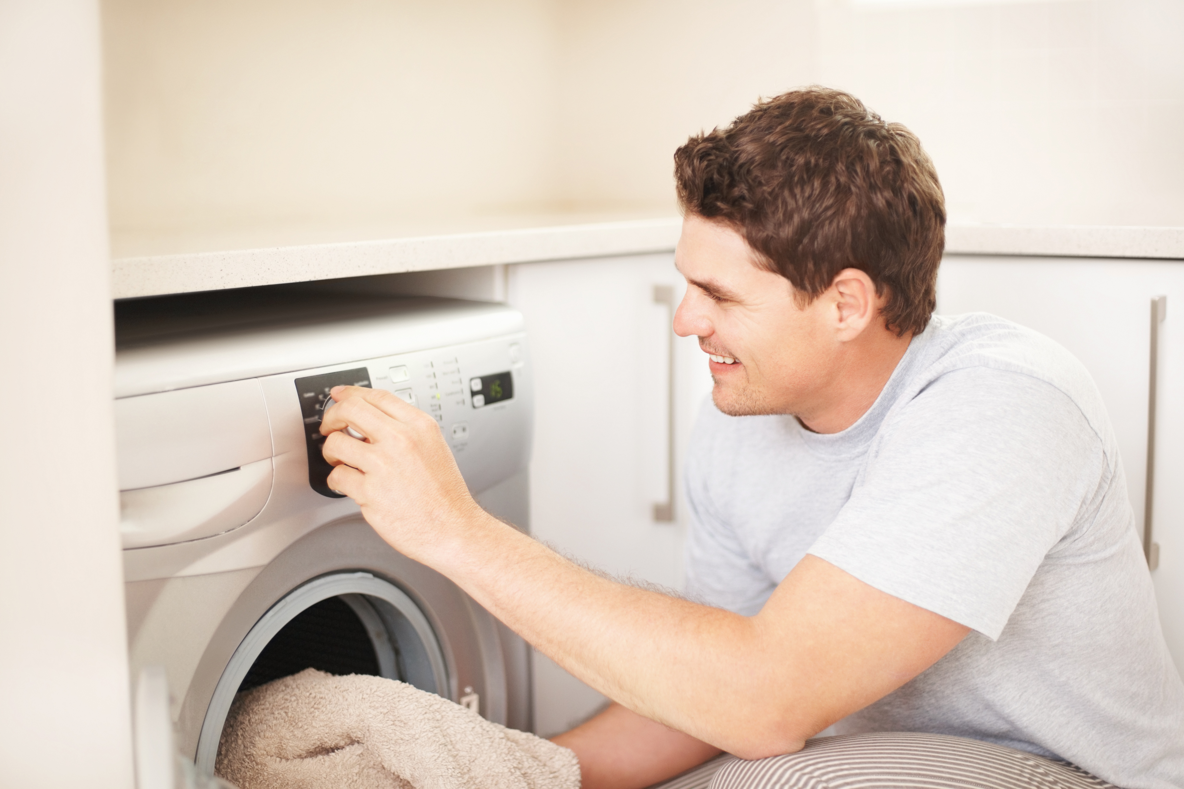 A man smiling while selecting a setting on a front load washer 