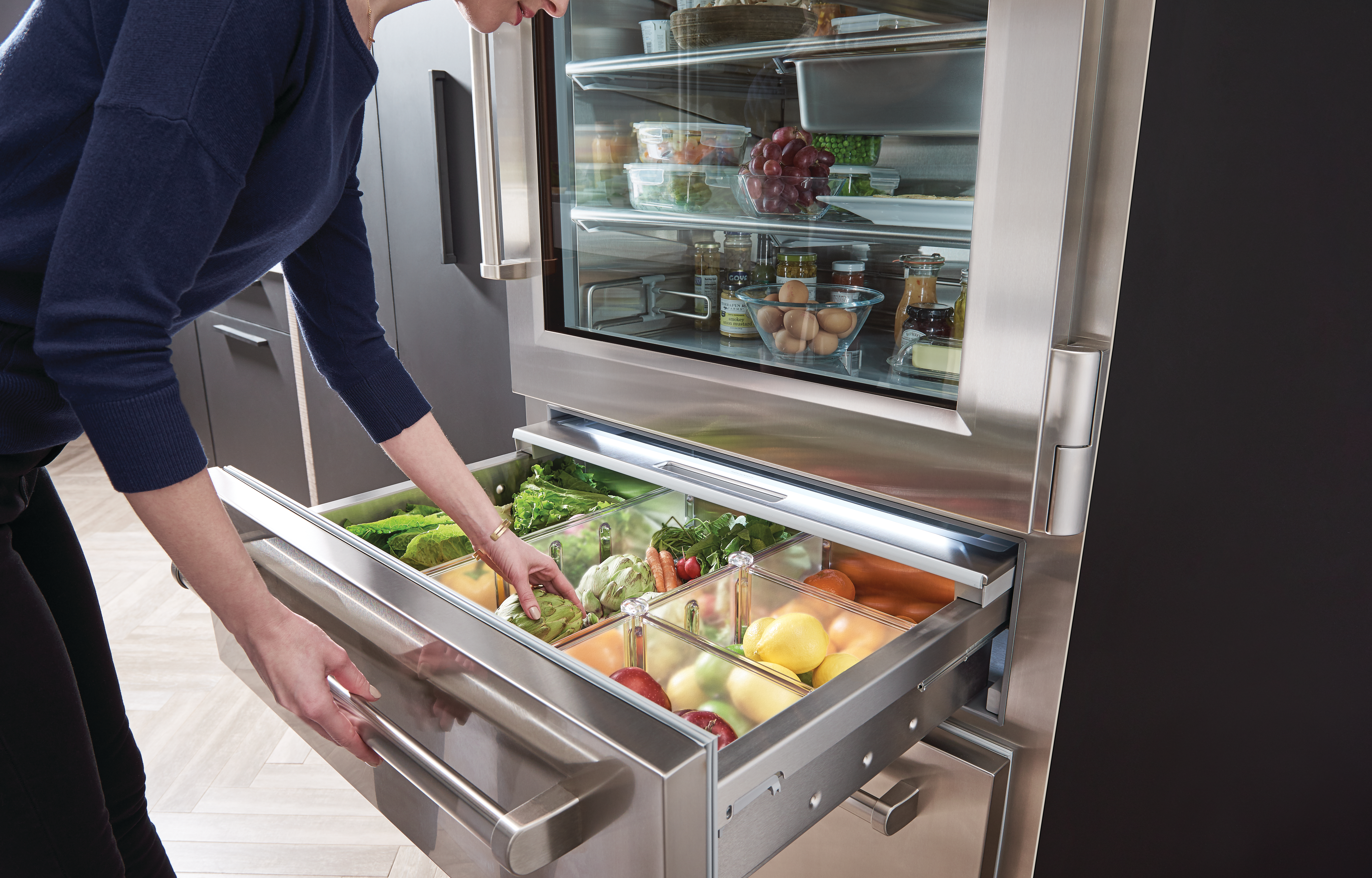 woman grabbing produce from sub zero PRO3650G pro series refrigerator middle drawer 