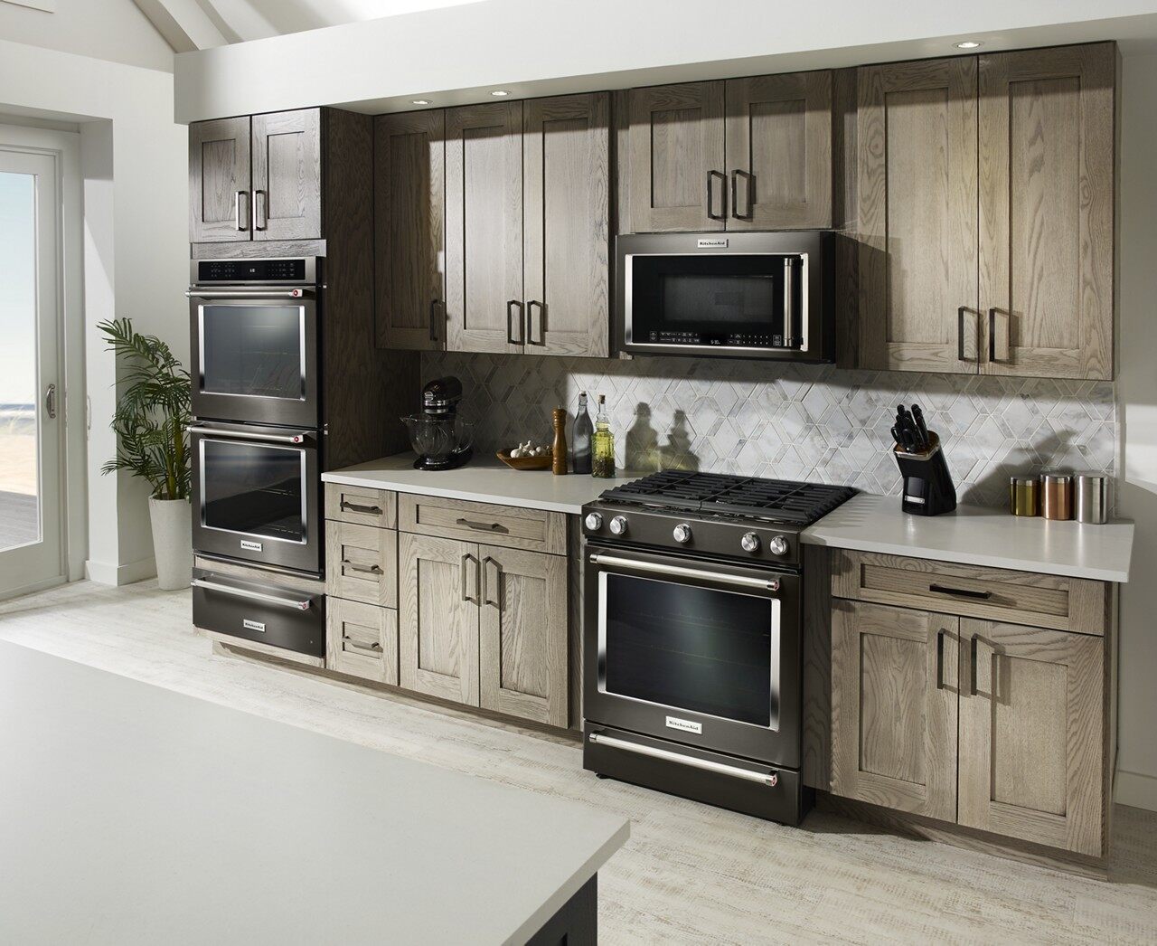 A kitchen featuring several KitchenAid appliances in black stainless steel 