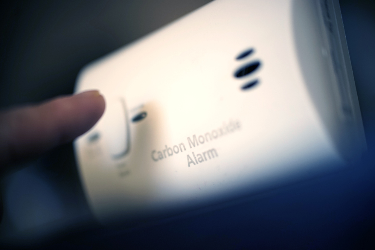 finger pressing button on carbon monoxide detector