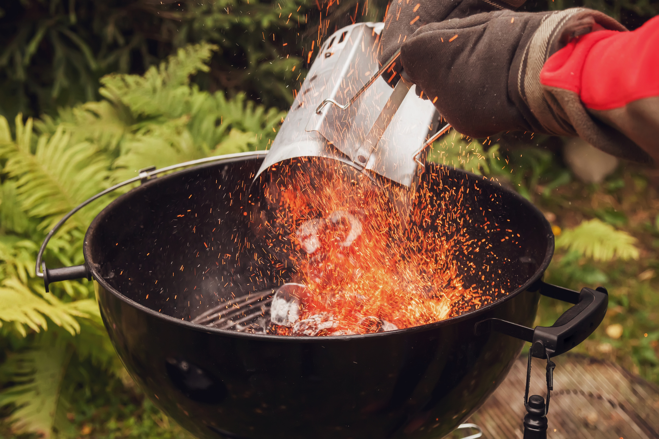 User pouring hot charcoal into grill with a chimney 