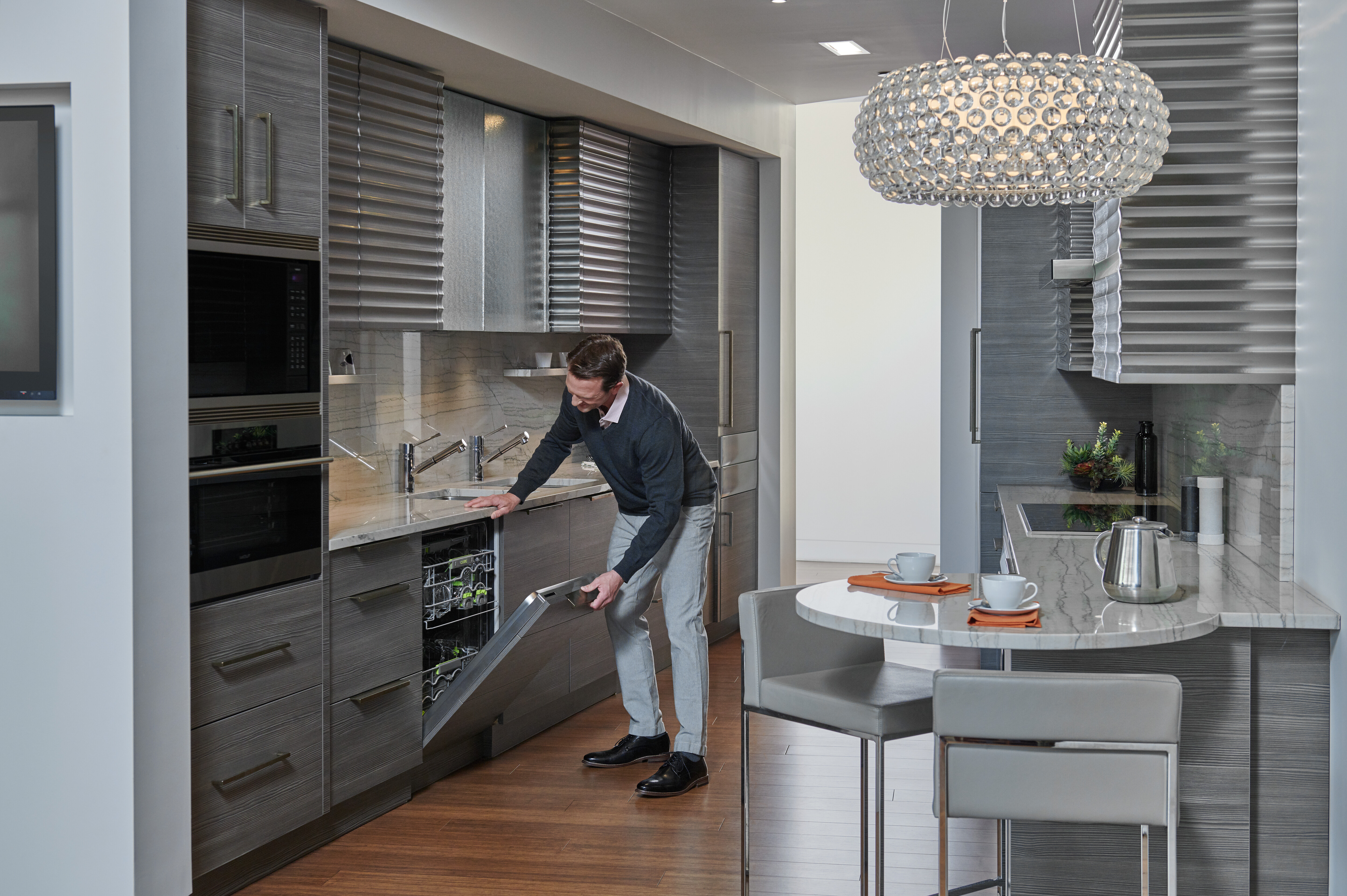 A man in a designer kitchen opening a Cove dishwasher 