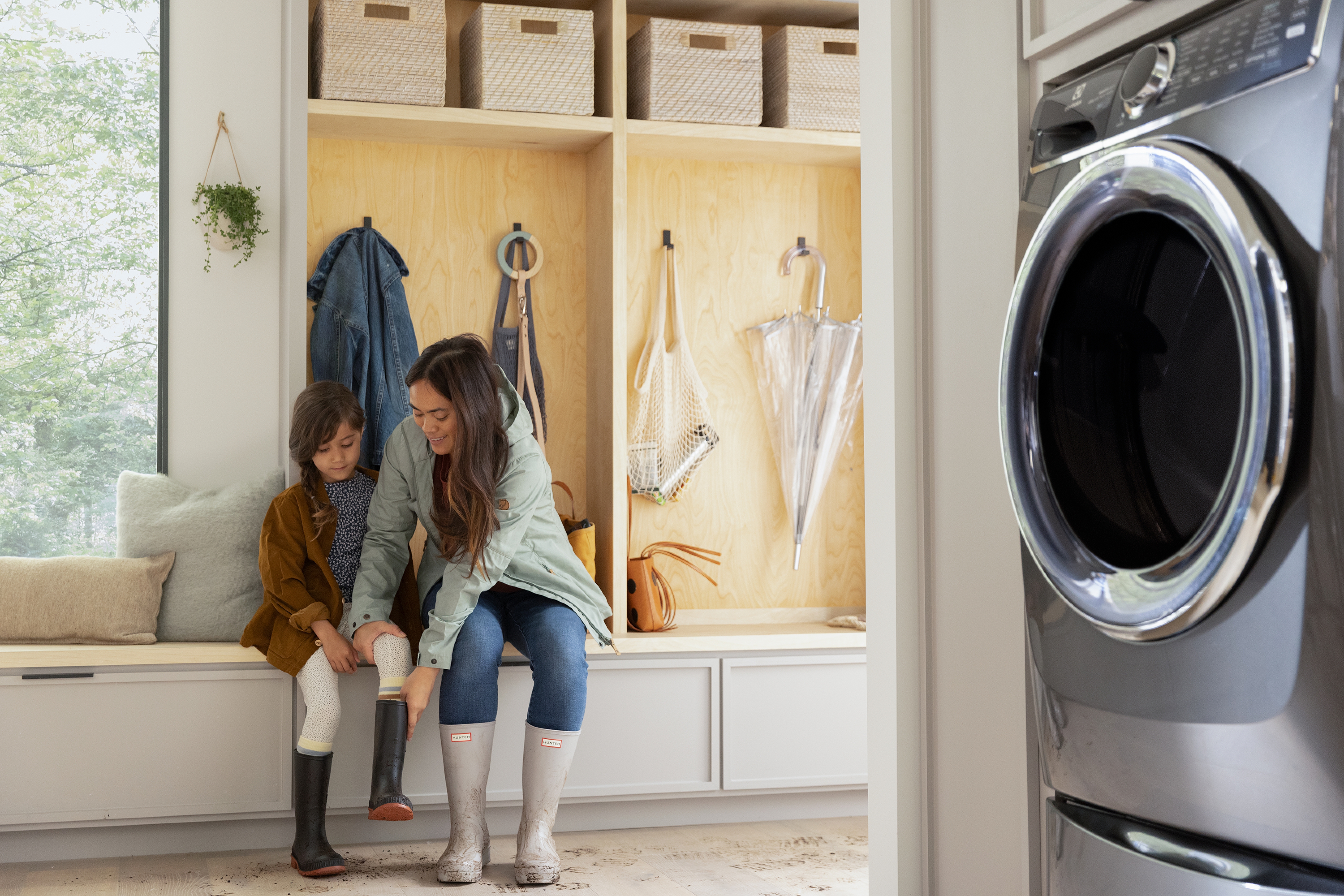 A woman and a child sitting in the background with an Electrolux washer in the foreground 
