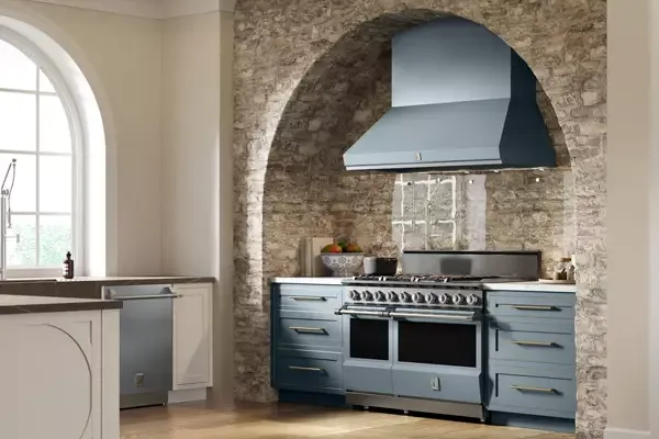 a luxury kitchen with a brick archway and gray hestan appliances