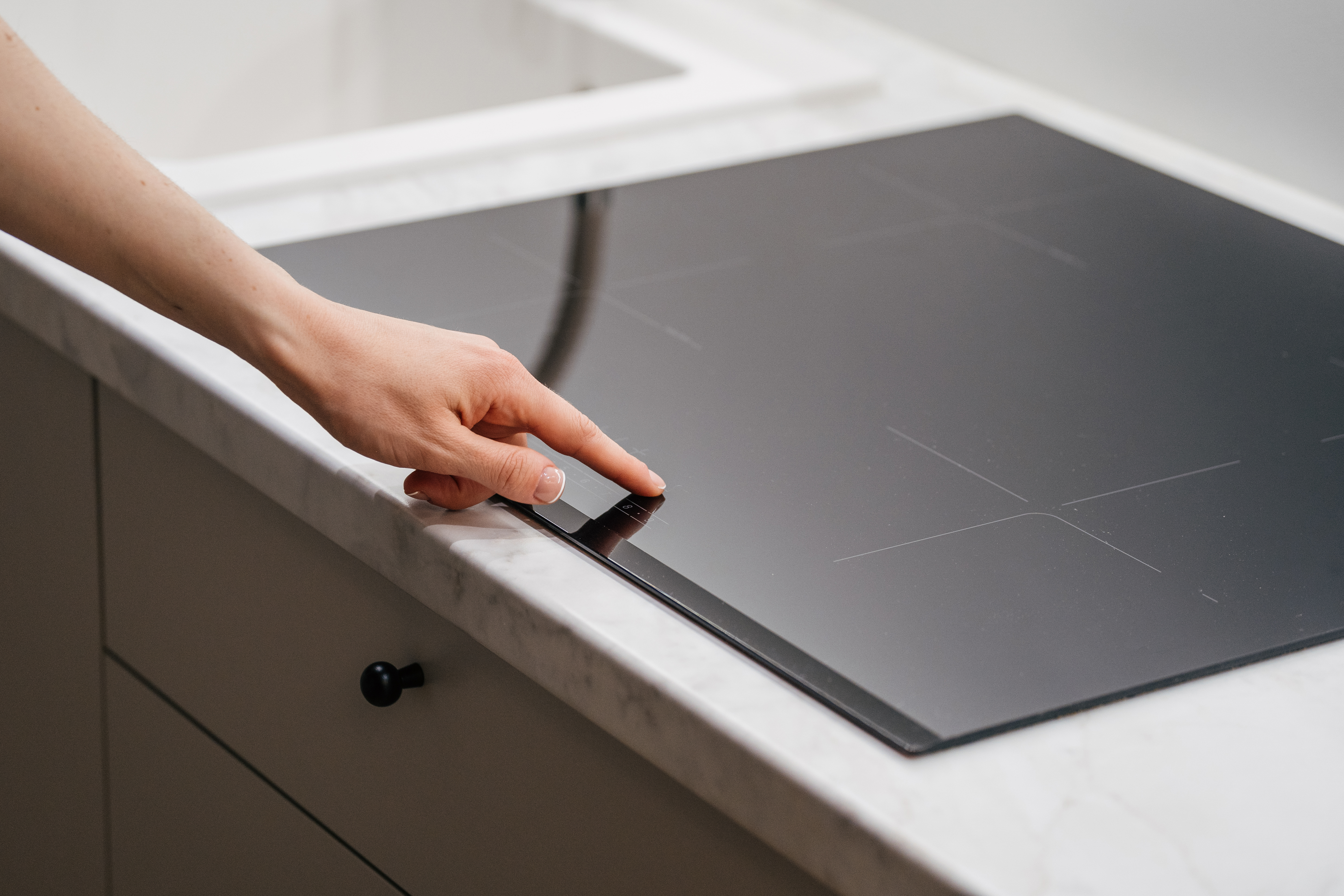 A person selecting a heat setting on an induction cooktop 