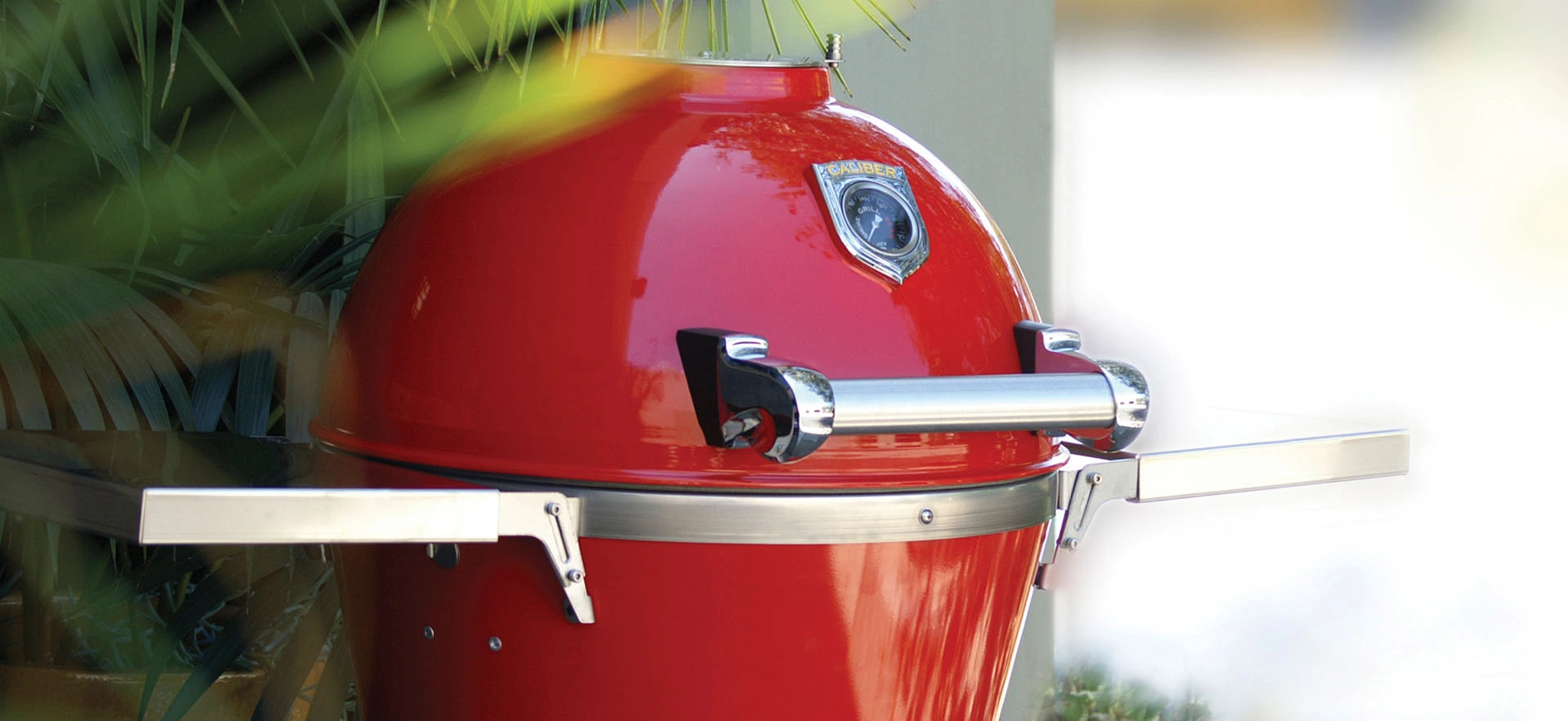 The Caliber Appliances 22” Pro Kamado grill seen outside next to plants 