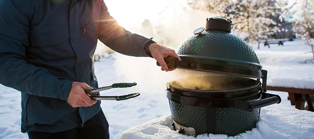 A person using the Big Green Egg 10” kamado grill in the snow 