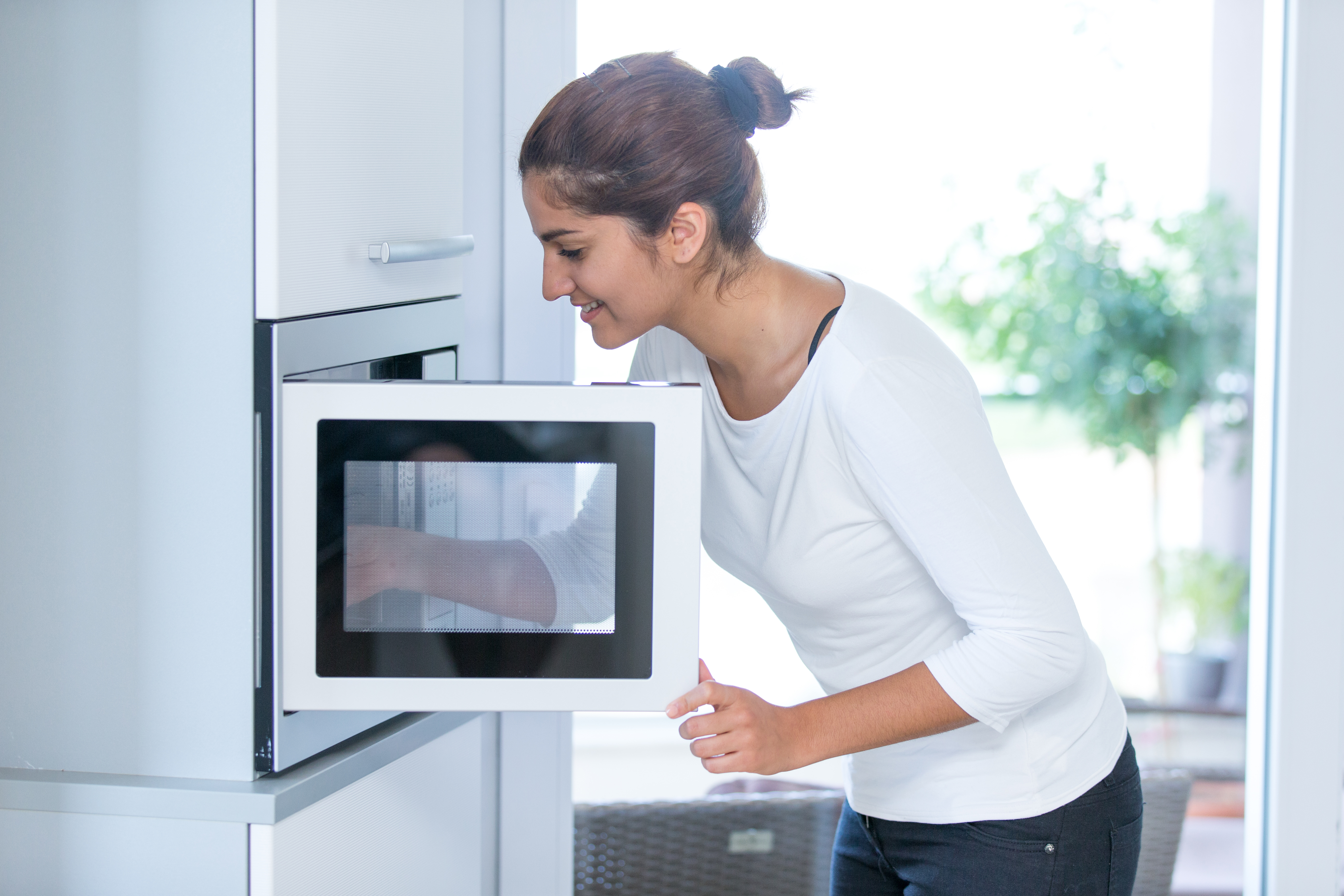 A woman smiling while using a built in microwave 