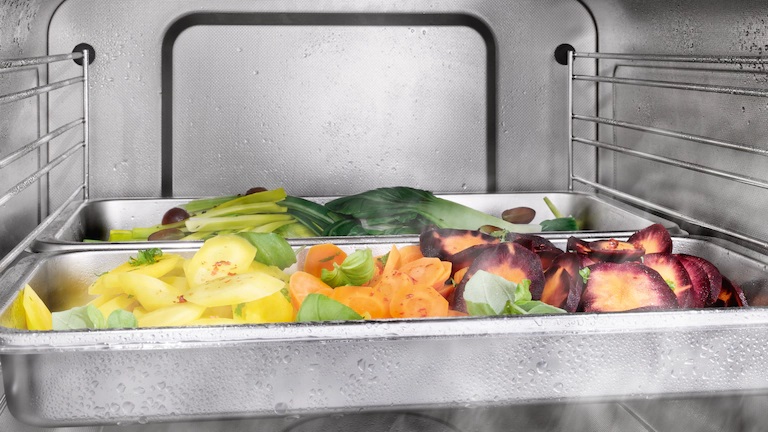 Close up shot of vegetables cooking inside a Miele steam oven 
