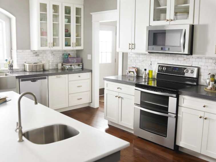 Double oven electric range with over the range microwave in a kitchen with grey walls