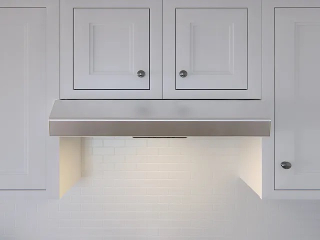 Zephyr AK1124S range hood shown installed into white cabinetry 