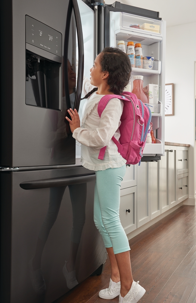 girl reaching in the fridge for a snack after school