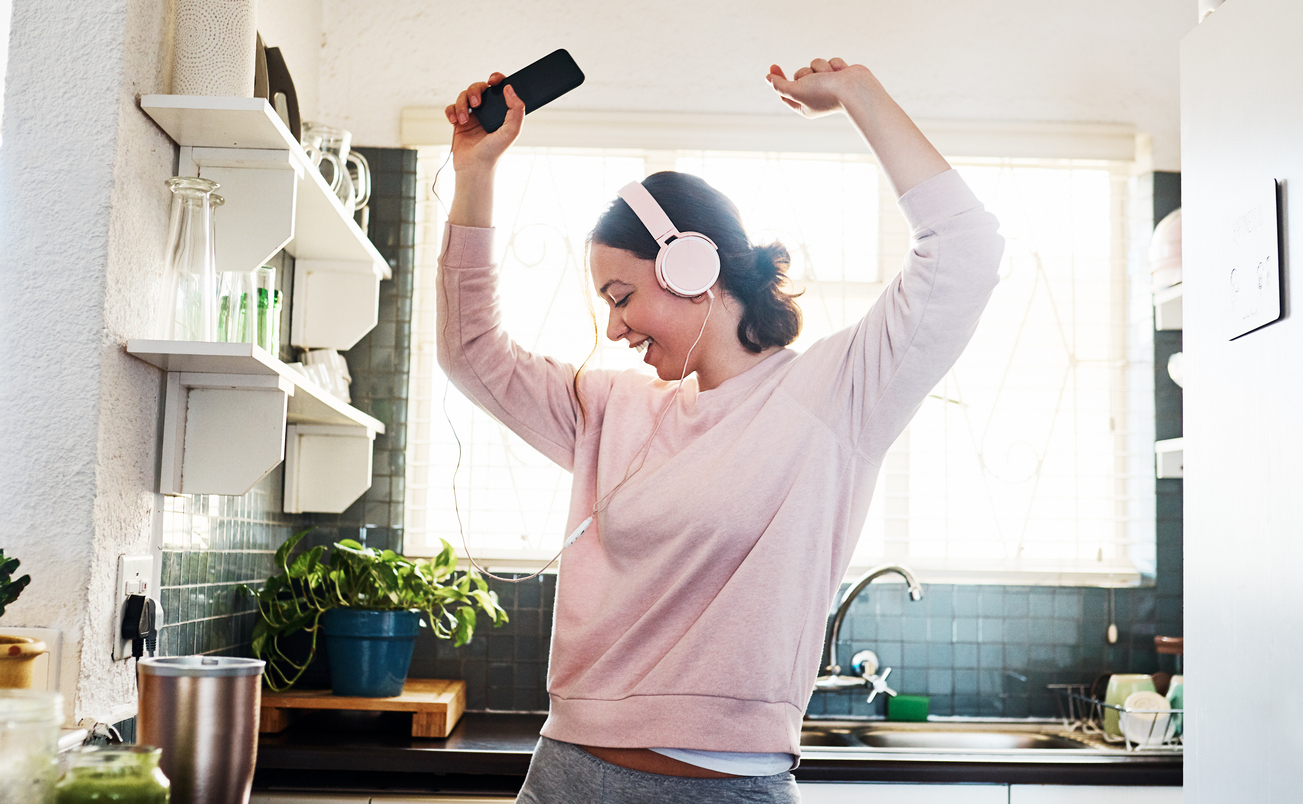 young woman listening to music through her headphones in the kitchen