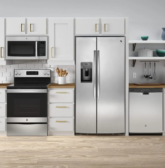 GE side by side refrigerator and other stainless steel GE appliances installed in a kitchen with white cabinets