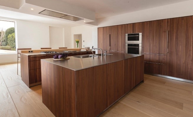 Two kitchen islands with stainless-steel countertops against all-wood wall cabinetry