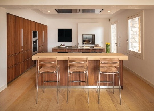 Three counter-height chairs positioned behind a countertop in a high-end modern kitchen