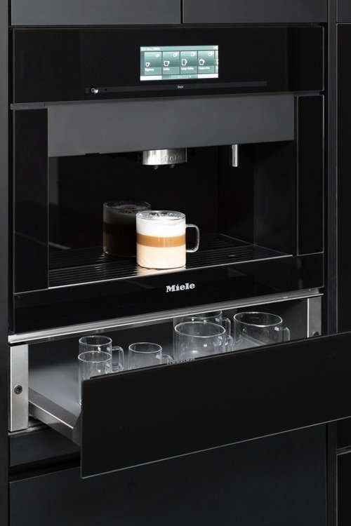 Up close look at a Miele built-in coffee maker and warmer drawer featured in a kitchen designed by Metro Design Build