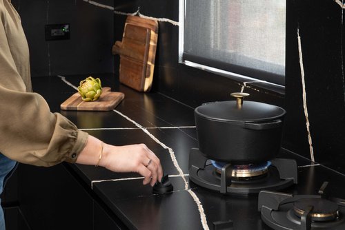Person cooking on the custom PII gas burners featured in a kitchen designed by Metro Design Build