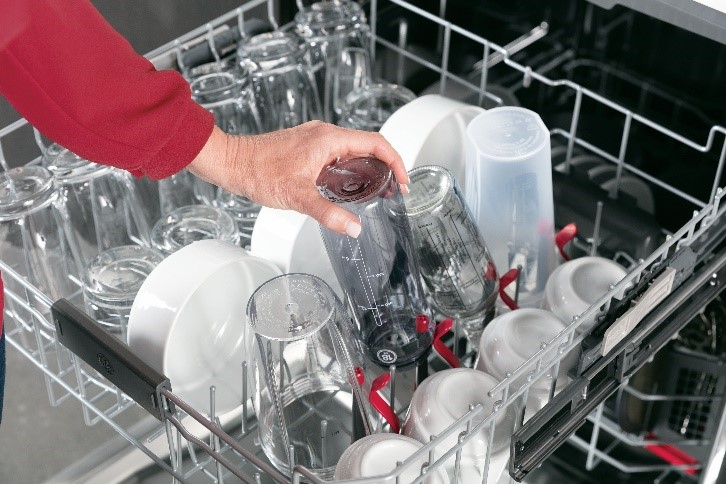 GE Profile product image of woman grabbing bottle from the four bottle jets on the top dishwasher rack