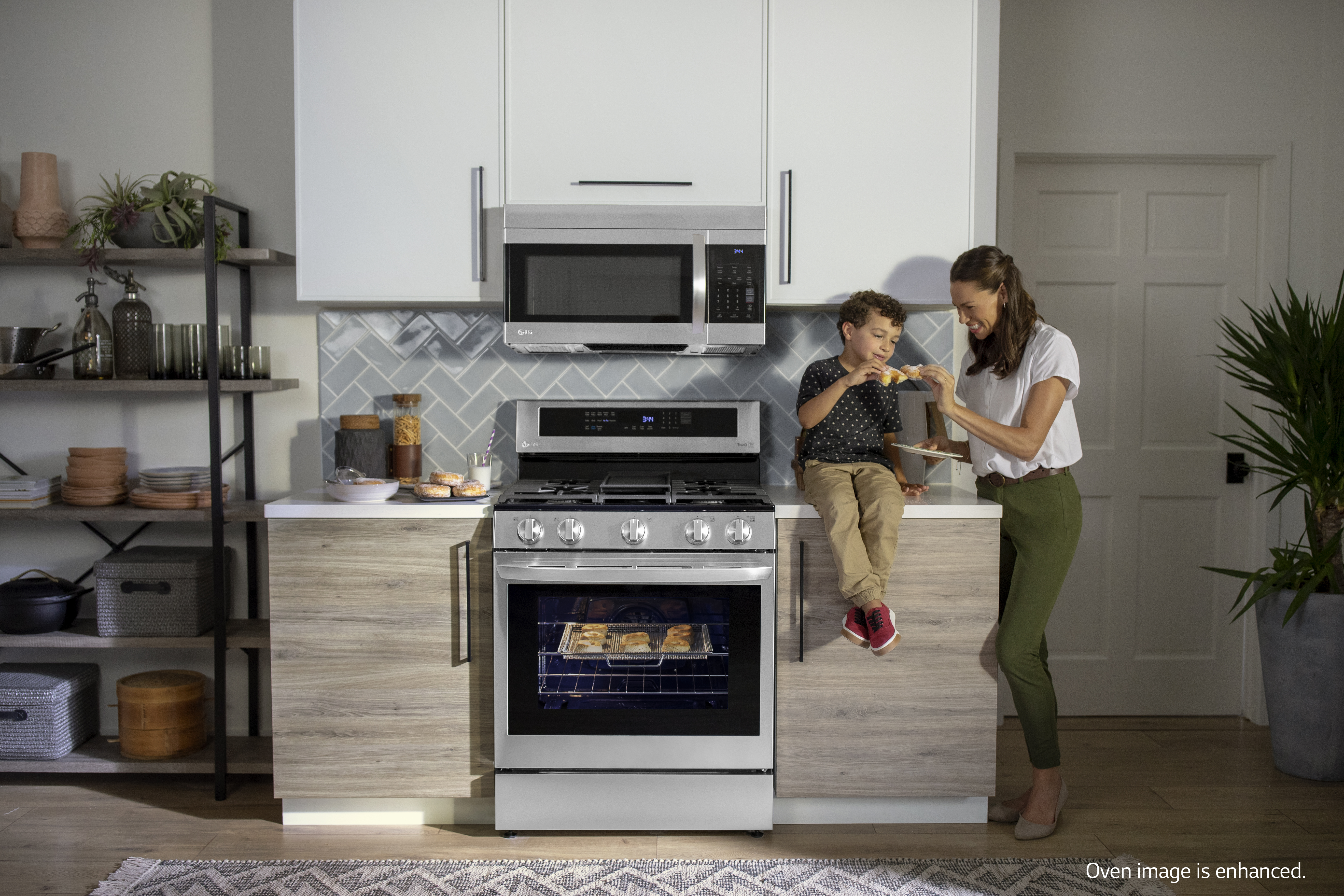 child on counter eating donuts with mother next to LG gas range and over-the-range microwave