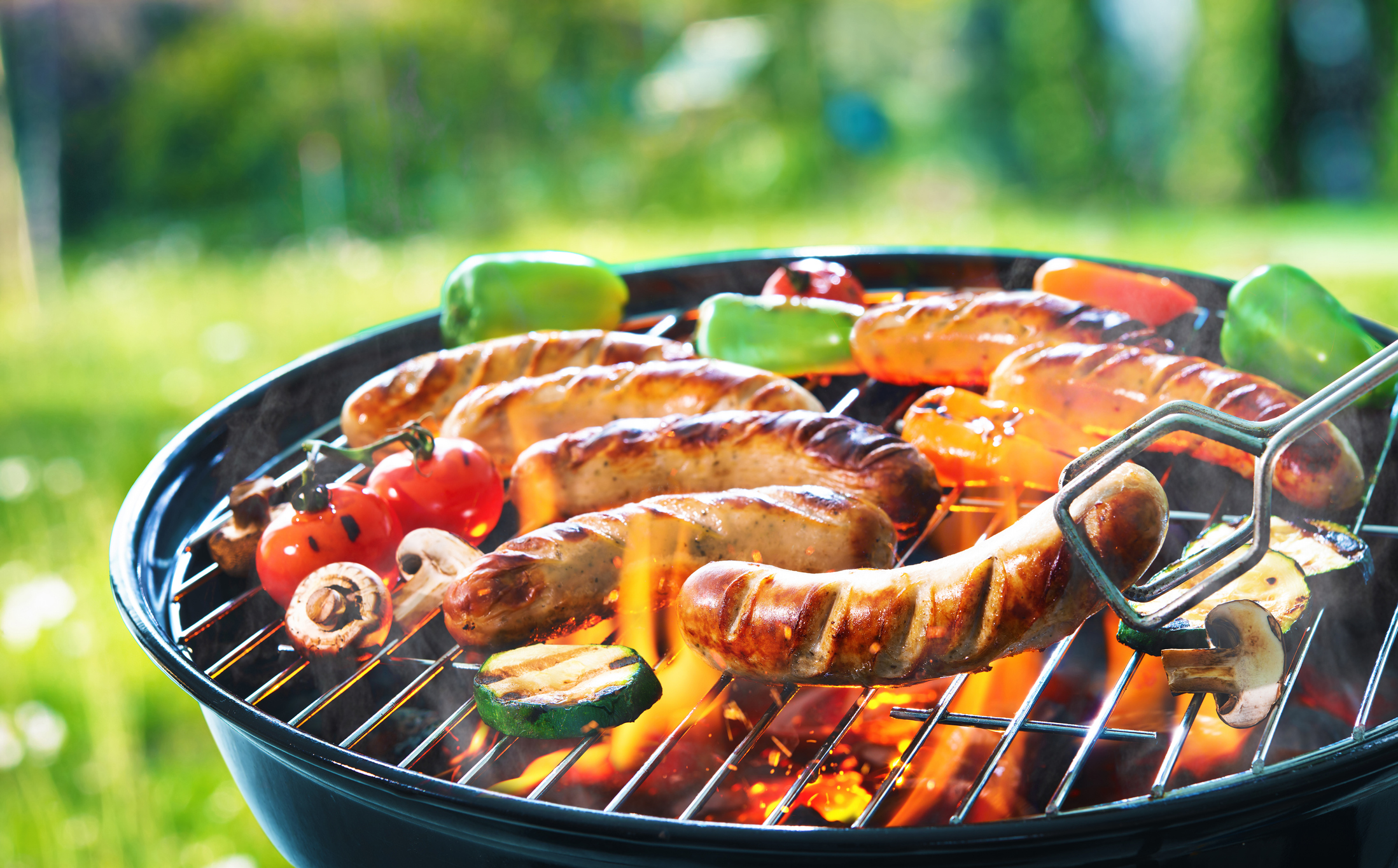 sausage and veggies cooking on a charcoal grill 