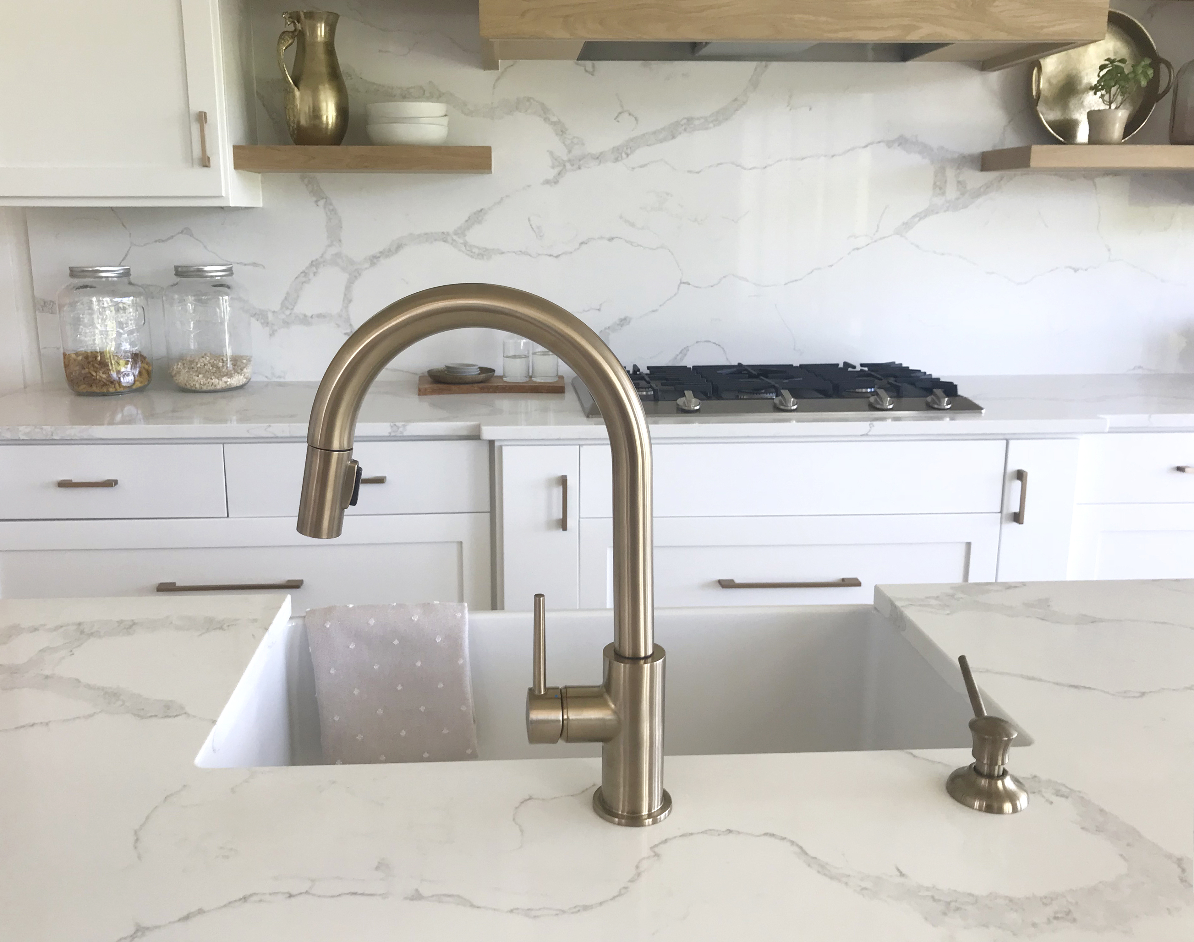 A quartz countertop with grey veins shown with a metal kitchen faucet 