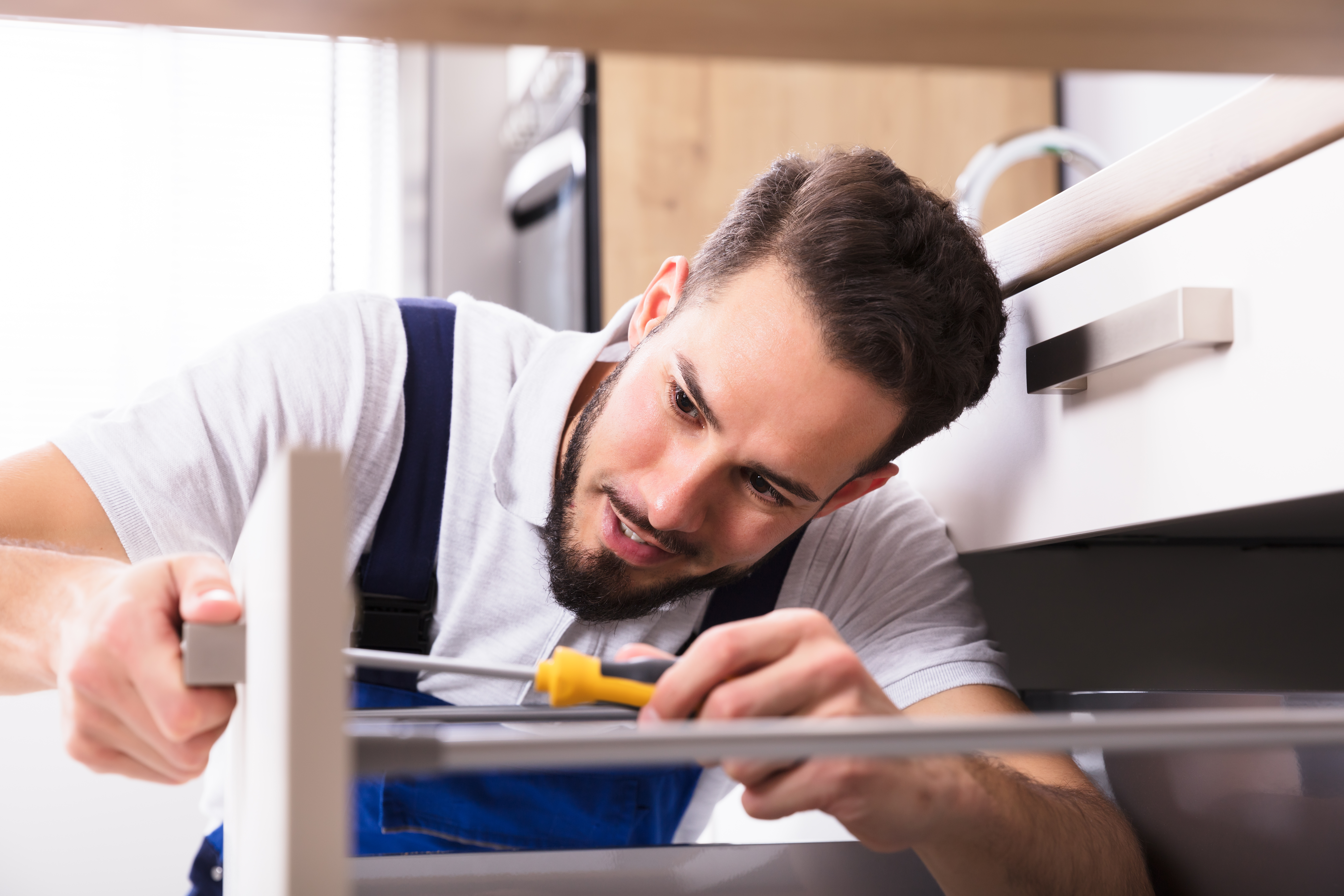 Young male carpenter installing new cabinet drawers 